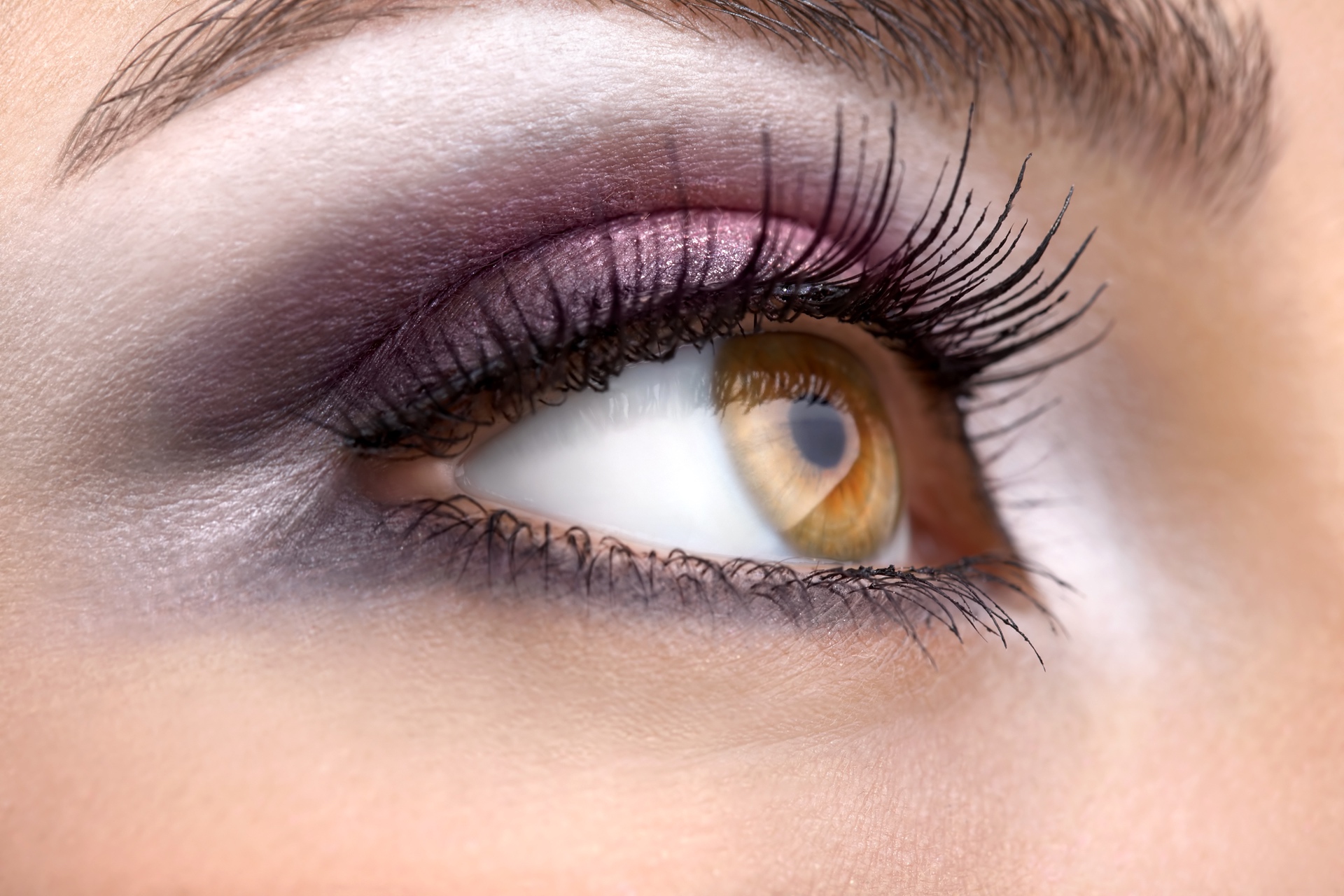 Close up of a woman's hazel coloured right eye with long eye lashes.