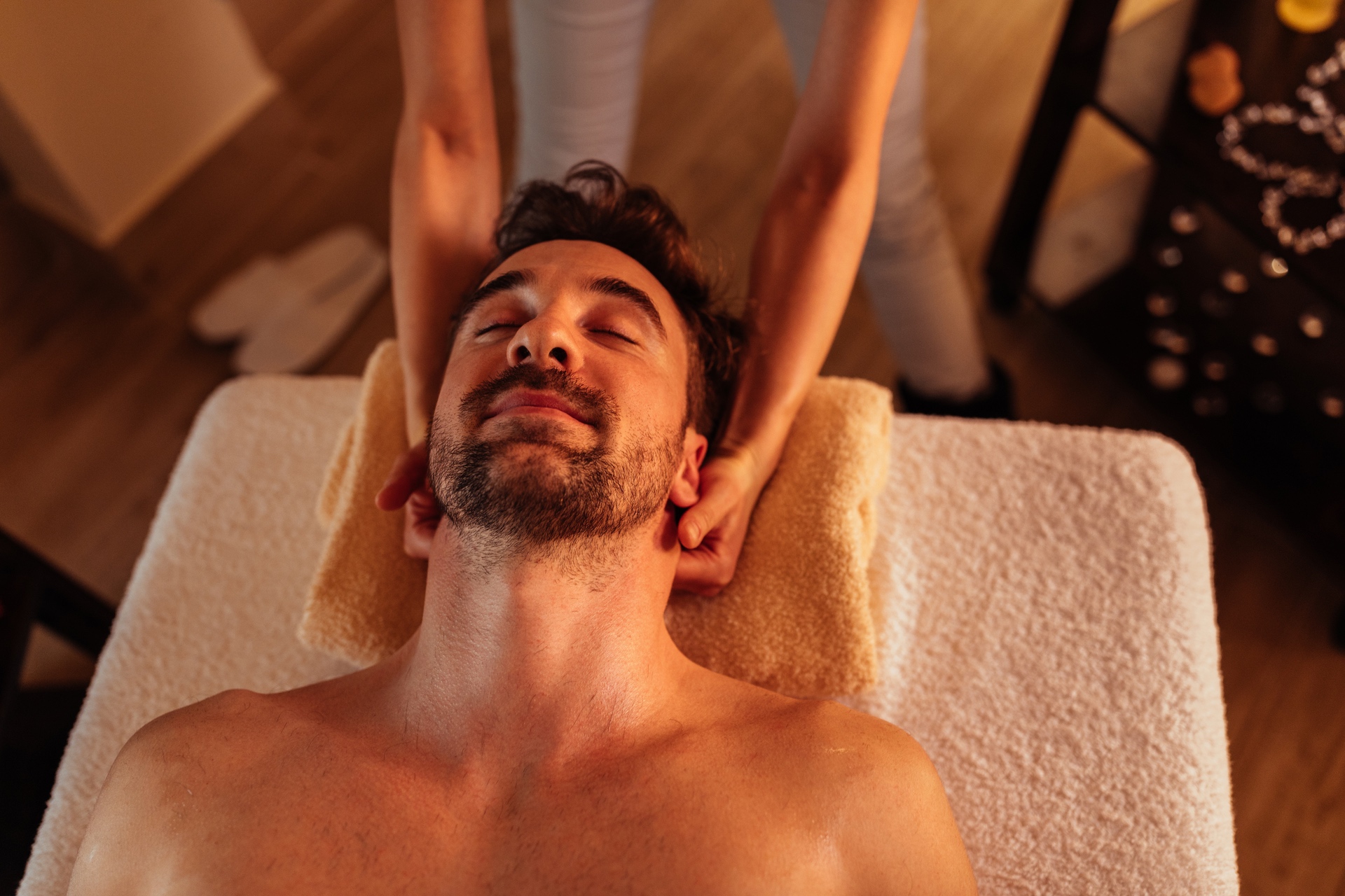 Close up shot of a young man with a beard enjoying a head massage at a spa