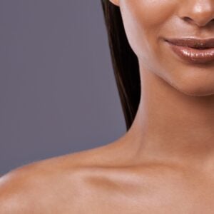 Close up of young woman with very clear skin and glossy lips.