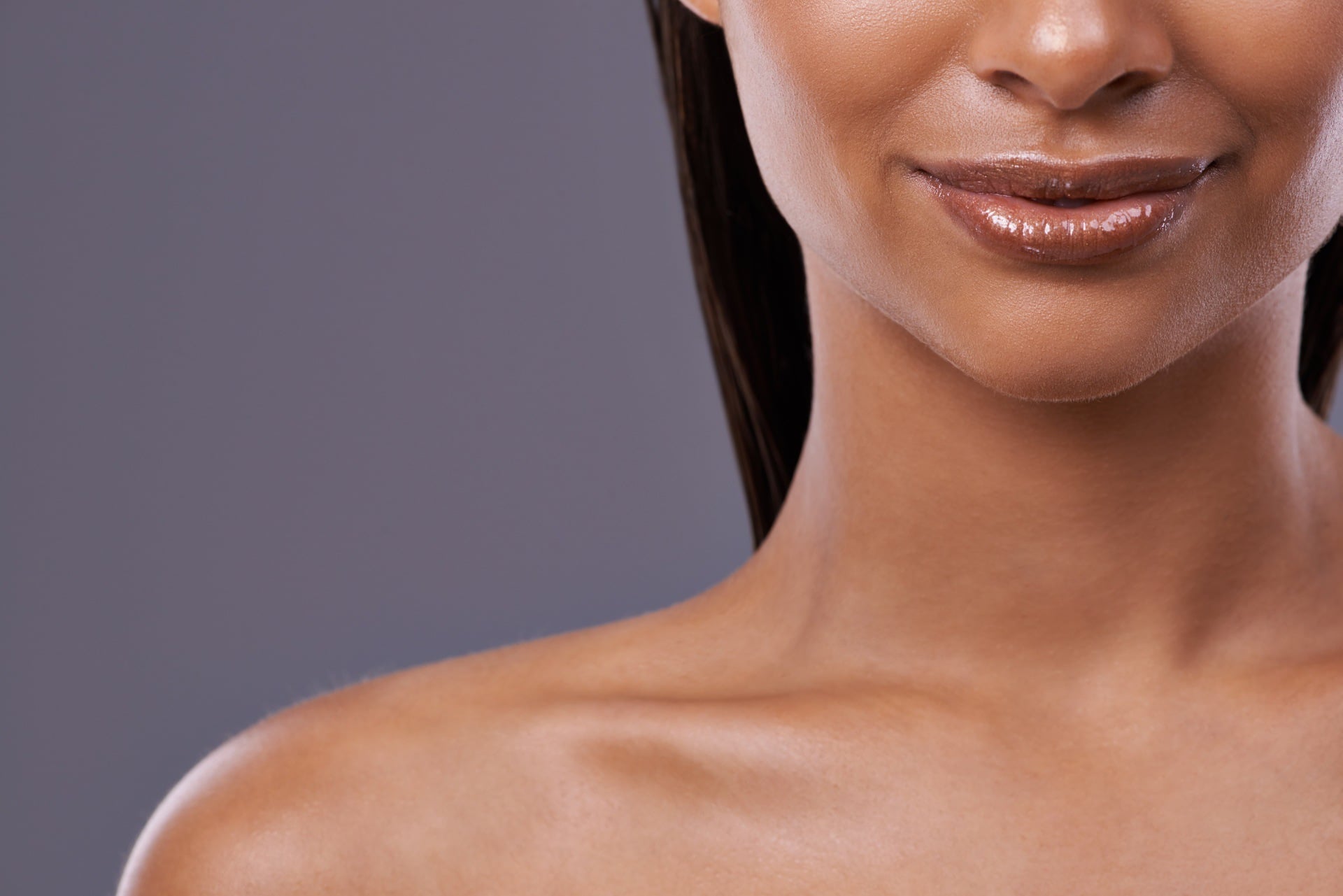 Close up of young woman with very clear skin and glossy lips.