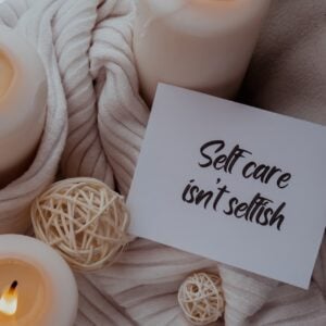 SELF CARE ISNT SELFISH text saying phrase on paper note on background of scented candles.